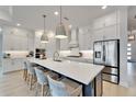 Modern kitchen with an island, stainless steel appliances, and white cabinets with elegant pendant lighting at 5971 Hidden Branch Dr, Apollo Beach, FL 33572