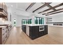 Modern kitchen boasts an island, stainless appliances, wood beams, and an electric fireplace at 937 Old Welcome Rd, Lithia, FL 33547