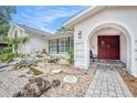Inviting front entrance featuring an arched entryway, rock garden and meticulously maintained landscape at 13310 Golf Crest Cir, Tampa, FL 33618