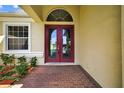 Red double front doors, brick pathway, and sidelight window offer curb appeal at 1835 Fircrest Ct, Wesley Chapel, FL 33543