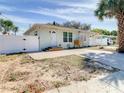 Street view of a light blue single-story home with a white fence and well-manicured yard at 1887 Springtime Ave, Clearwater, FL 33755