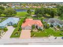 Expansive aerial view featuring a beautiful home with a tile roof, manicured lawn, and paver driveway in a lakeside community at 2221 Platinum Dr, Sun City Center, FL 33573