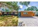 Attractive home with a brick driveway, updated siding, and a charming front yard deck seating area at 412 Mira Vista Dr, Dunedin, FL 34698