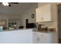 Kitchen with white cabinets, vaulted ceiling, and view to the living room at 4206 Revere Cir, New Port Richey, FL 34653