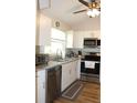 Well-equipped kitchen with stainless steel dishwasher and microwave, and bright white cabinets at 4206 Revere Cir, New Port Richey, FL 34653