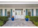 Charming front entrance with blue shutters, potted plants, and a decorative glass-paneled front door at 511 Windward Psge, Clearwater Beach, FL 33767