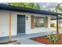 Inviting front entrance featuring a black door, wood shutters, and fresh landscaping at 6304 S S Grady Ave, Tampa, FL 33616