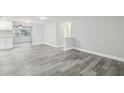 Open concept living area with modern gray flooring, light walls, and seamless flow to the adjacent kitchen at 9011 Hunt Club Ln, Port Richey, FL 34668