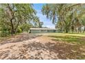 Single story home with large front yard, gravel driveway and mature trees with Spanish moss at 9819 Allen Rd, Lithia, FL 33547