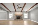 Open living room featuring wood beams, a stone fireplace, two windows, and laminate wood flooring at 1510 Patricia Ave, Dunedin, FL 34698