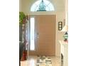 Front door with sidelight and transom window bringing in natural light to greet guests at 1607 Alexander Crossing Way, Sun City Center, FL 33573