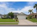 Inviting one-story home with lush green lawn, tidy landscaping, and a two-car garage at 1607 Alexander Crossing Way, Sun City Center, FL 33573