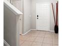 Bright foyer with neutral tile flooring, adjacent staircase, and modern decor at 17509 Queensland St, Land O Lakes, FL 34638