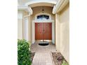 Close-up of the double front door with an overhead light, tiled entryway, and manicured bushes at 19743 Ellendale Dr, Land O Lakes, FL 34638