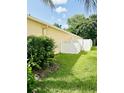 Side yard showing well-kept lawn, mature greenery, and a white fence for privacy at 19743 Ellendale Dr, Land O Lakes, FL 34638