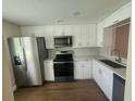 Updated kitchen featuring white cabinets, stainless steel appliances, and wood flooring at 209 Corkwood Ln, Oldsmar, FL 34677