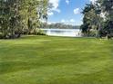 Expansive backyard with lush lawn and mature trees bordering a serene lake at 2103 N Golfview Dr, Plant City, FL 33566