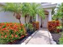 Charming front entrance adorned with vibrant landscaping, stone walkway, and double palm trees for added privacy at 2228 Hannah S Way, Dunedin, FL 34698