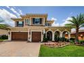 Beautiful two-story home featuring a three-car garage, arched entryway, and manicured landscaping at 29038 Picana Ln, Wesley Chapel, FL 33543