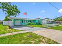 A well-maintained turquoise home with a carport, American flag, and neatly landscaped lawn at 5107 Pine St, Seffner, FL 33584