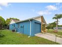 Side view of the home showing the matching blue garage door, siding, and well maintained lawn at 7810 Flintlock Dr, Port Richey, FL 34668