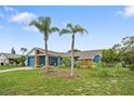 Inviting front yard featuring well-manicured lawn and mature palm trees enhancing the curb appeal at 7810 Flintlock Dr, Port Richey, FL 34668