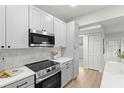 Renovated kitchen boasts white cabinets, stainless steel appliances, and new flooring at 8485 Pelican Ln, Seminole, FL 33777