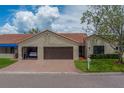 Villa showing the driveway leading to the garage, with barrel tile roof and manicured lawn at 8701 40Th N Ln, Pinellas Park, FL 33782