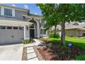 Two-story home with neutral facade, features a two-car garage, and a well-manicured lawn with stepping stone walkway at 31111 Bridgegate Dr, Wesley Chapel, FL 33545