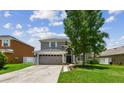 Charming two-story home with a well-maintained lawn, large tree, and neutral-colored facade, featuring a two-car garage at 31111 Bridgegate Dr, Wesley Chapel, FL 33545