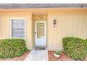 Close-up of a home's front door with decorative plants, a welcome mat, and tidy landscaping at 11511 113Th St # 33D, Largo, FL 33778