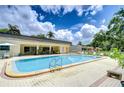 Community pool with lounge chairs, tables, and umbrellas on a sunny day with landscaping at 11511 113Th St # 33D, Largo, FL 33778