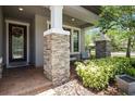 Inviting front porch with stone pillars and neutral chairs for relaxing in front of the home at 12415 Hitching St, Odessa, FL 33556