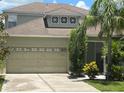 Close-up of charming home featuring a two-car garage with beautiful tropical landscaping at 1247 Gentilly Ln, Wesley Chapel, FL 33544