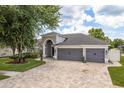 Charming single-story home featuring a well-manicured lawn, gray garage doors, and a brick-paved driveway at 16226 Carnoustie Dr, Odessa, FL 33556