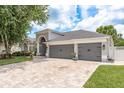 Charming single-story home featuring a well-manicured lawn, gray garage doors, and a brick-paved driveway at 16226 Carnoustie Dr, Odessa, FL 33556