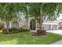 Charming single-story home featuring a well-manicured lawn and colorful flowerbeds in front at 16226 Carnoustie Dr, Odessa, FL 33556