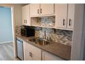 Charming kitchen features tile backsplash, stainless steel appliances, and bright white cabinets at 219 Pompano Se Dr # D, St Petersburg, FL 33705