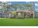 Charming home featuring lush lawn, mature landscaping, and a wooden fence, showcasing curb appeal at 3106 E Diana St, Tampa, FL 33610