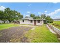 View of the home's exterior from the backyard, showing green grass and a wood deck at 37732 Cecil Ln, Zephyrhills, FL 33542