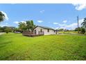 Backyard view featuring a green lawn, wood deck, and the home's exterior with blue skies at 37732 Cecil Ln, Zephyrhills, FL 33542
