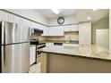 Well-lit kitchen featuring white cabinets, stainless steel appliances, and speckled granite countertops at 504 S Armenia Ave # 1329B, Tampa, FL 33609