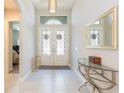 Bright foyer with decorative glass doors, complemented by a glass table, mirror, and neutral decor at 6331 Voyagers Pl, Apollo Beach, FL 33572