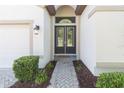 Inviting entryway featuring double doors with glass inserts, enhanced by manicured bushes and a brick walkway at 6331 Voyagers Pl, Apollo Beach, FL 33572
