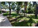 Spacious front yard with mature trees and lush green lawn, complemented by a sidewalk at 7684 Oakhurst Rd, Seminole, FL 33776