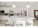 Modern kitchen with stainless steel appliances, a center island with seating, and stylish pendant lighting at 10463 Abaco Falls Dr, Englewood, FL 34223