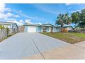 This single-story home features a long driveway, attached garage, and mature palm tree at 1051 Pert Ln, Holiday, FL 34691