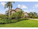 Beautifully landscaped home with a terracotta roof and a three-car garage with mature trees at 165 Mobbly Bay Dr, Oldsmar, FL 34677