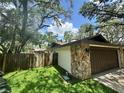 Attached garage featuring a wooden door and stone accent wall, adjacent to a lawn at 2102 Doefield Ct, Valrico, FL 33596