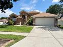 Exterior shot of a single-Gathering home with manicured lawn, mature landscaping, and a paved driveway leading to a garage at 28826 Windover St, Wesley Chapel, FL 33545